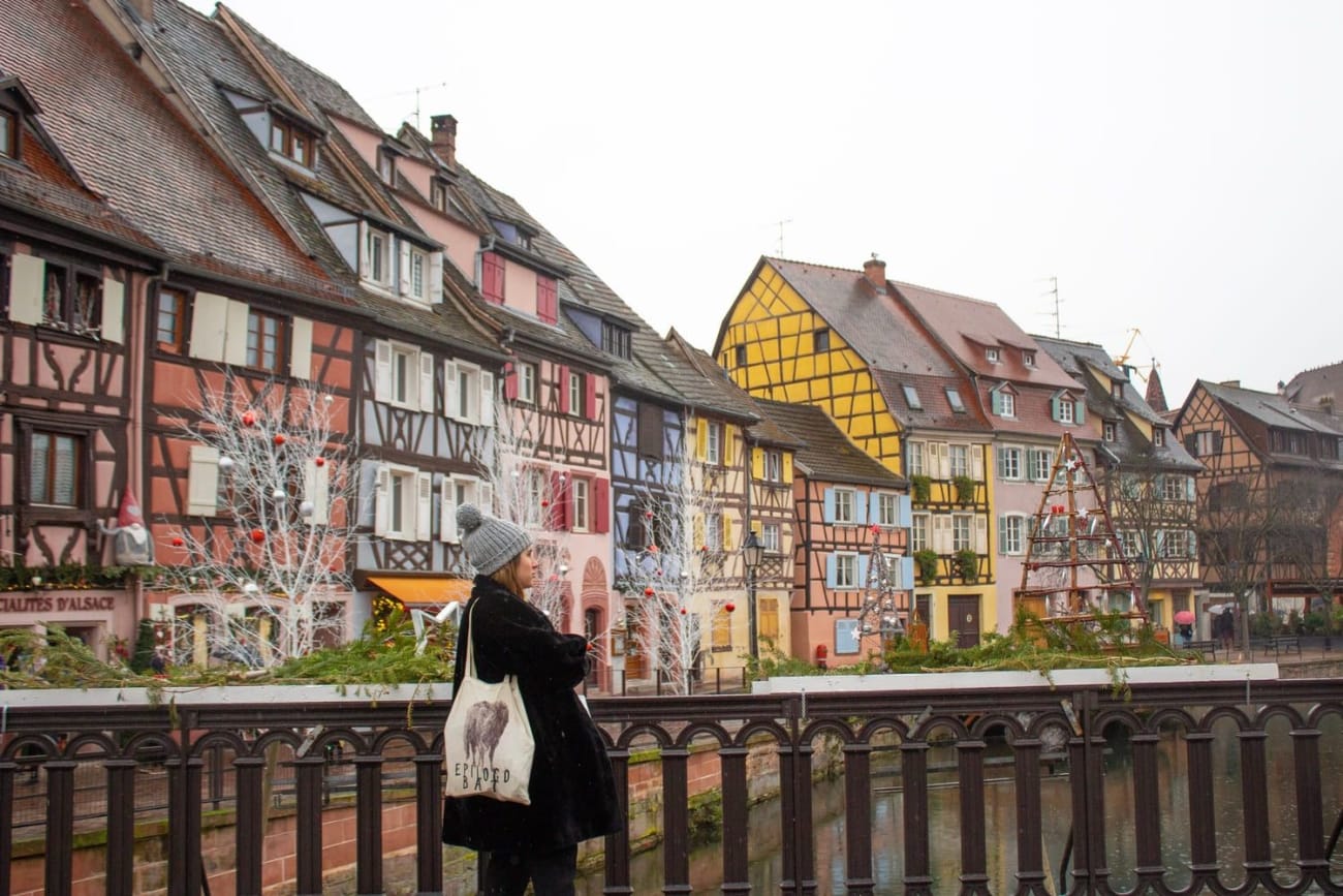 Top balades Noël Alsace : femme avec bonnet sur pont en bois près de maisons à colombages