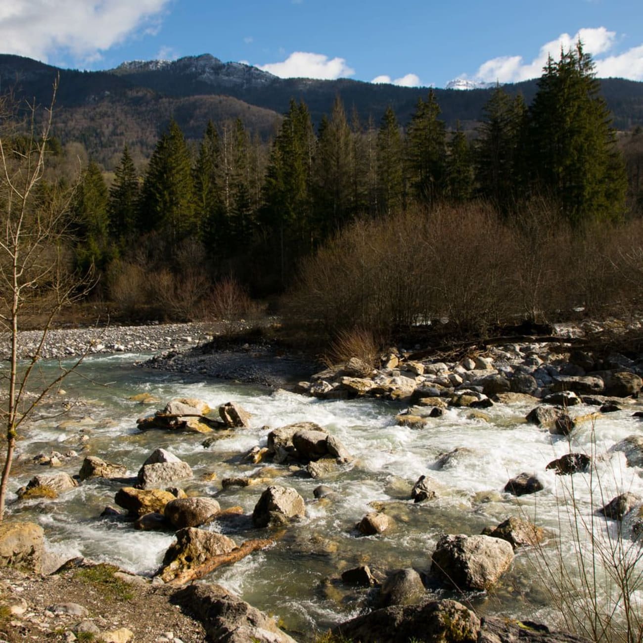 Randonnée cascade du Pissieu : rivière d'eau claire parsemée de pierres avec montagnes au fond
