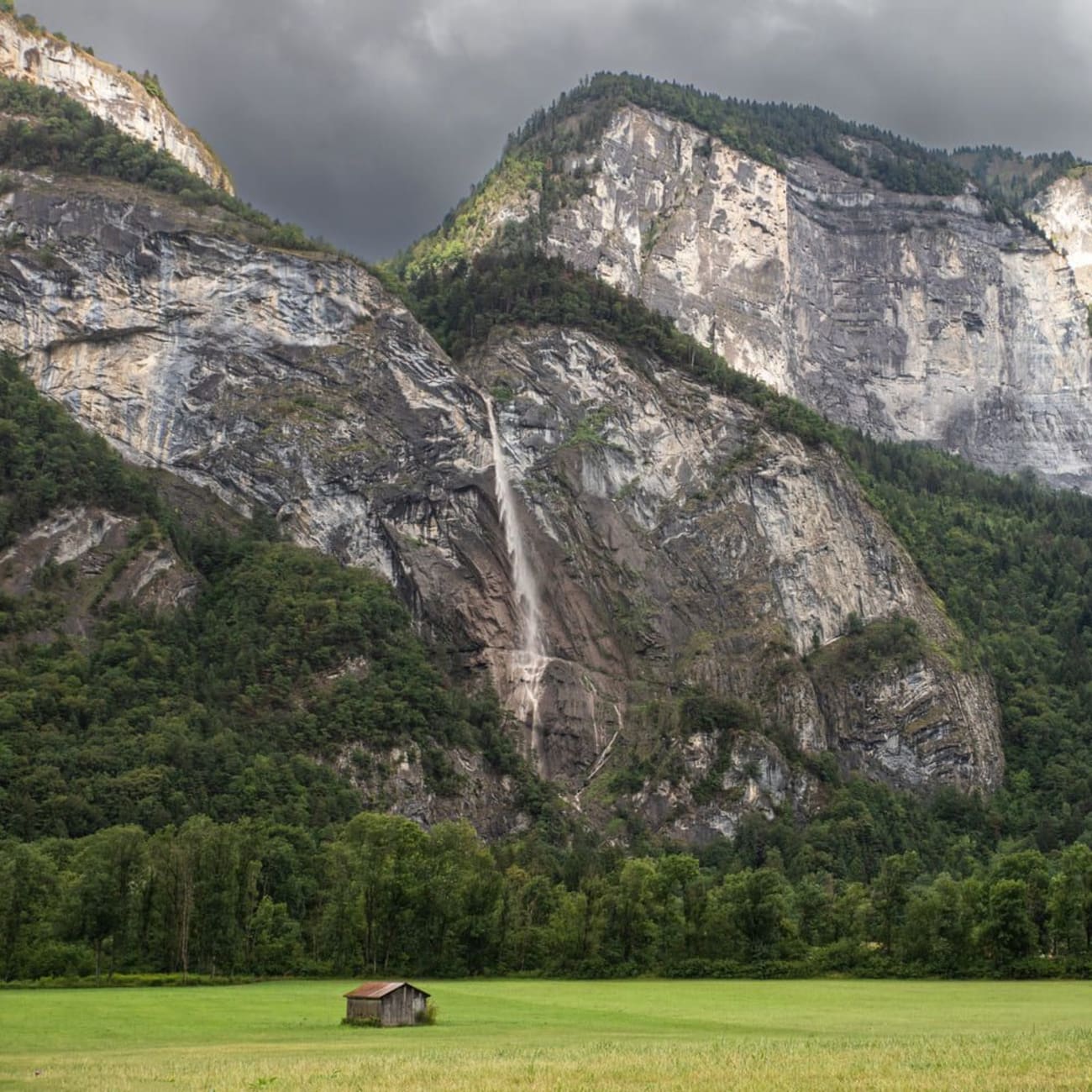 Randonnée cascade de l'Arpenaz : maison en bois sur herbe au pied de montagnes avec chute d'eau