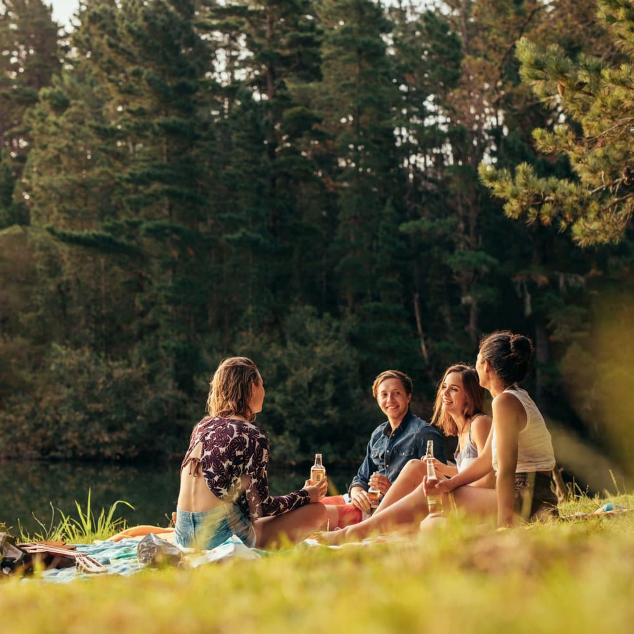 Randonnée été : quatre personnes assises dans l'herbe qui pique-niquent