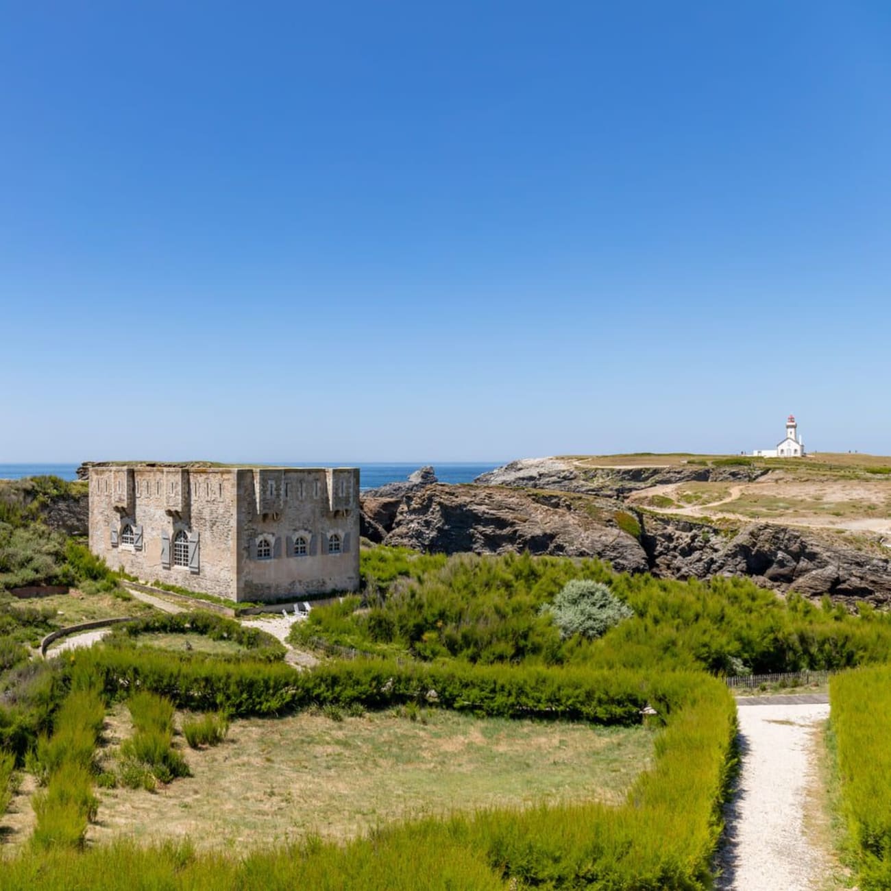 Randonnée pointe des Poulains : fort rectangulaire entouré de végétation verdoyante, phare et mer en arrière-plan