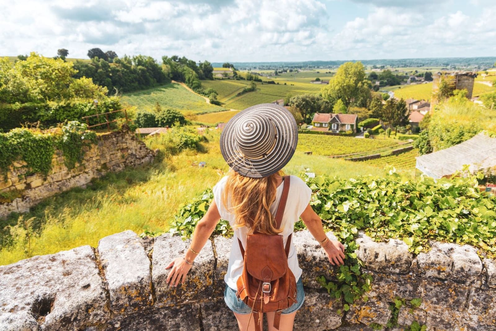 Randonnée transports en commun Bordeaux : femme de dos avec chapeau regardant les prairies vertes