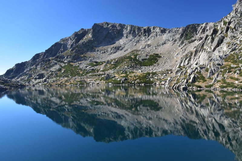 Randonnée lac de Bastani : montagne se reflétant dans un lac lisse