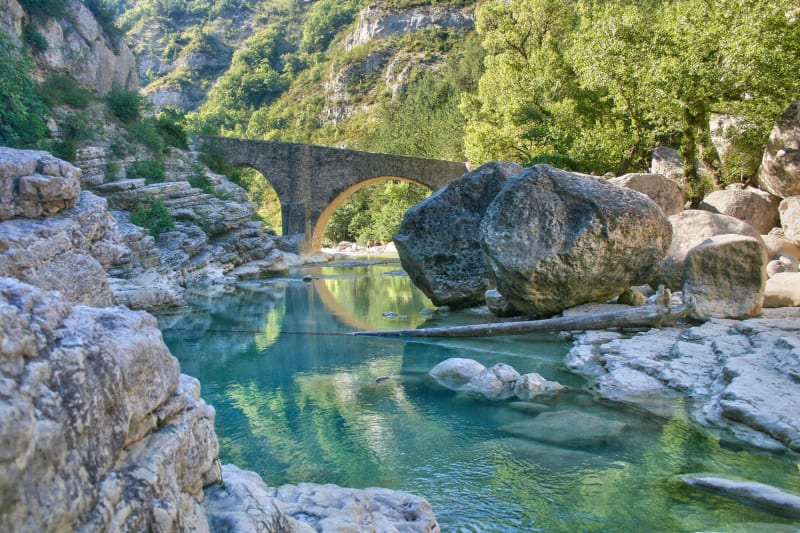 Randonnée gorges de la Méouge : eau cristalline serpentant entre blocs de roche et sous un pont