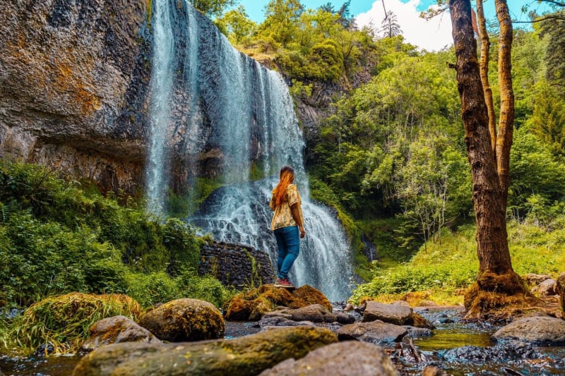 Randonnée cascades Haute-Loire : femme face à chutes d'eau avec végétation autour