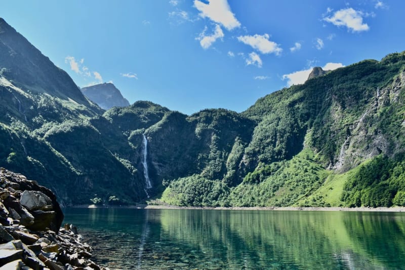 Randonnée lac d'Oô : eau turquoise entourée de montagnes verdoyantes et cascade au fond