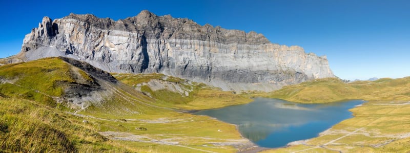 Randonnée lac d'Anterne : étendue d'eau bleue entourée de pelouse et d'une montagne acérée