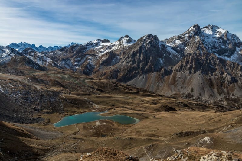 Randonnée lac des Cerces : étendue d'eau bleue entourée de végétation marron et de montagnes saupoudrées de neige