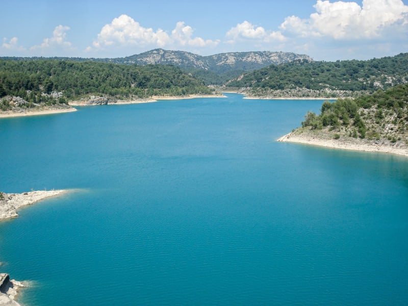 Randonnée lac de Bimont : grande étendue d'eau bleue entourée de buissons verts et montagnes au loin