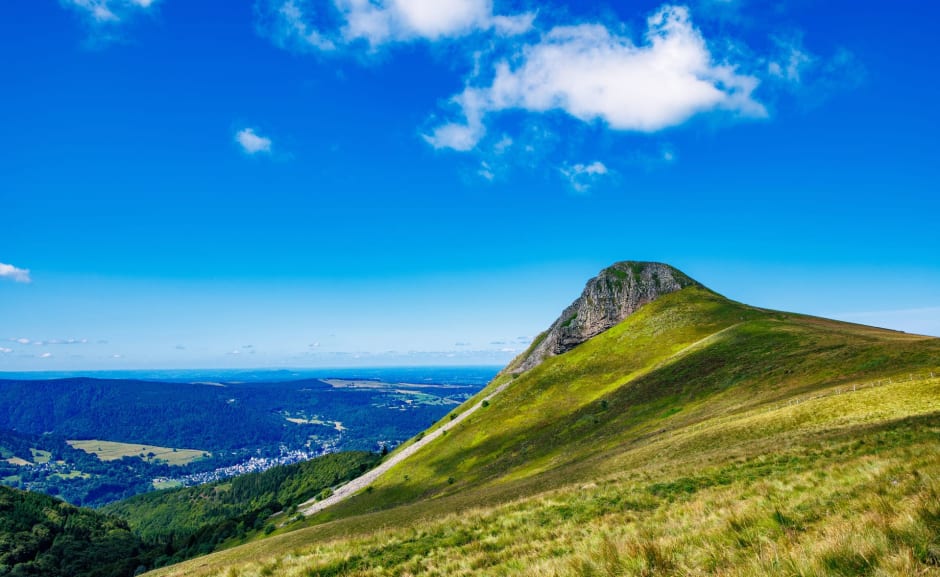 Randonnée banne d'Ordanche : sommet entouré de pâturages dominant la ville sous un ciel bleu