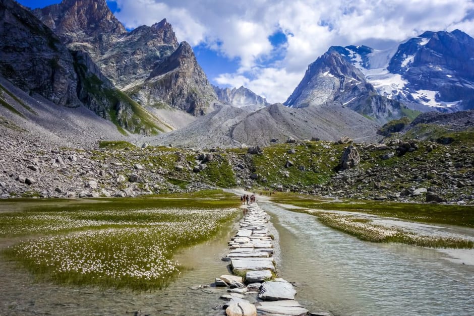 Randonnée lac des Vaches : dalles de pierres traversant le lac face aux sommets de la Vanoise