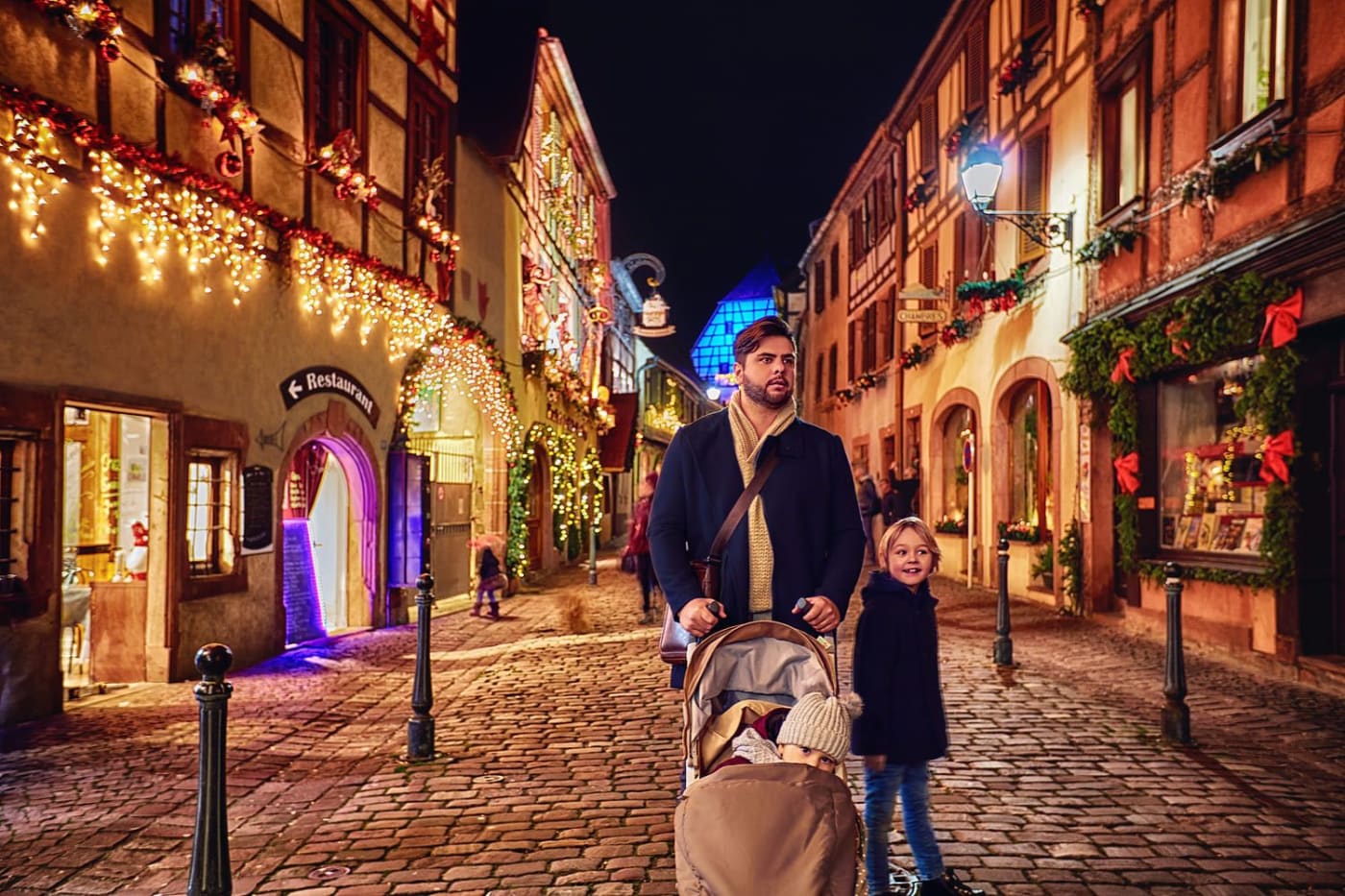 Marché de Noël de Kaysersberg en Alsace : un homme et ses enfants se baladent entre les maisons à colombages