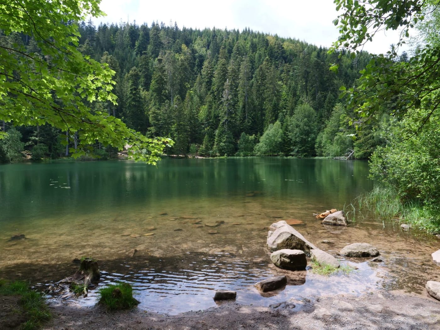 Randonnée lac de la Maix : eau vert émeraude, blocs de pierre et végétation verte autour