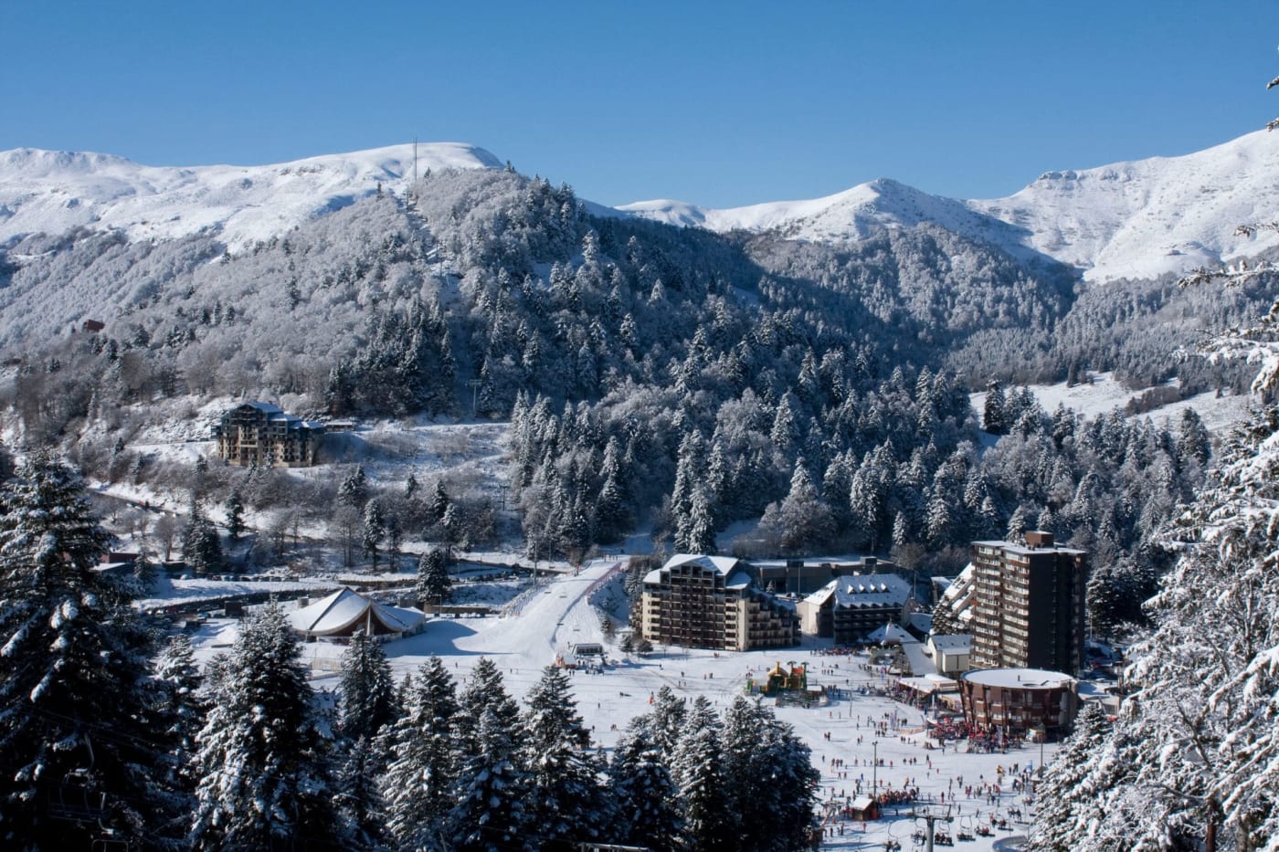 Vacances hiver raquettes : village de montagne entouré d'arbres et de montagnes enneigés