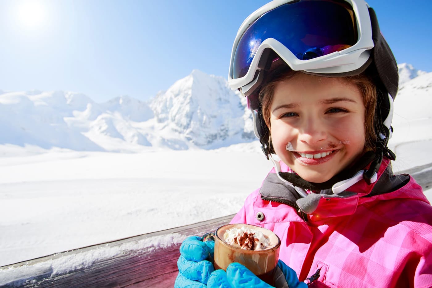 Vacances hiver raquettes : fillette buvant un chocolat chaud à la neige