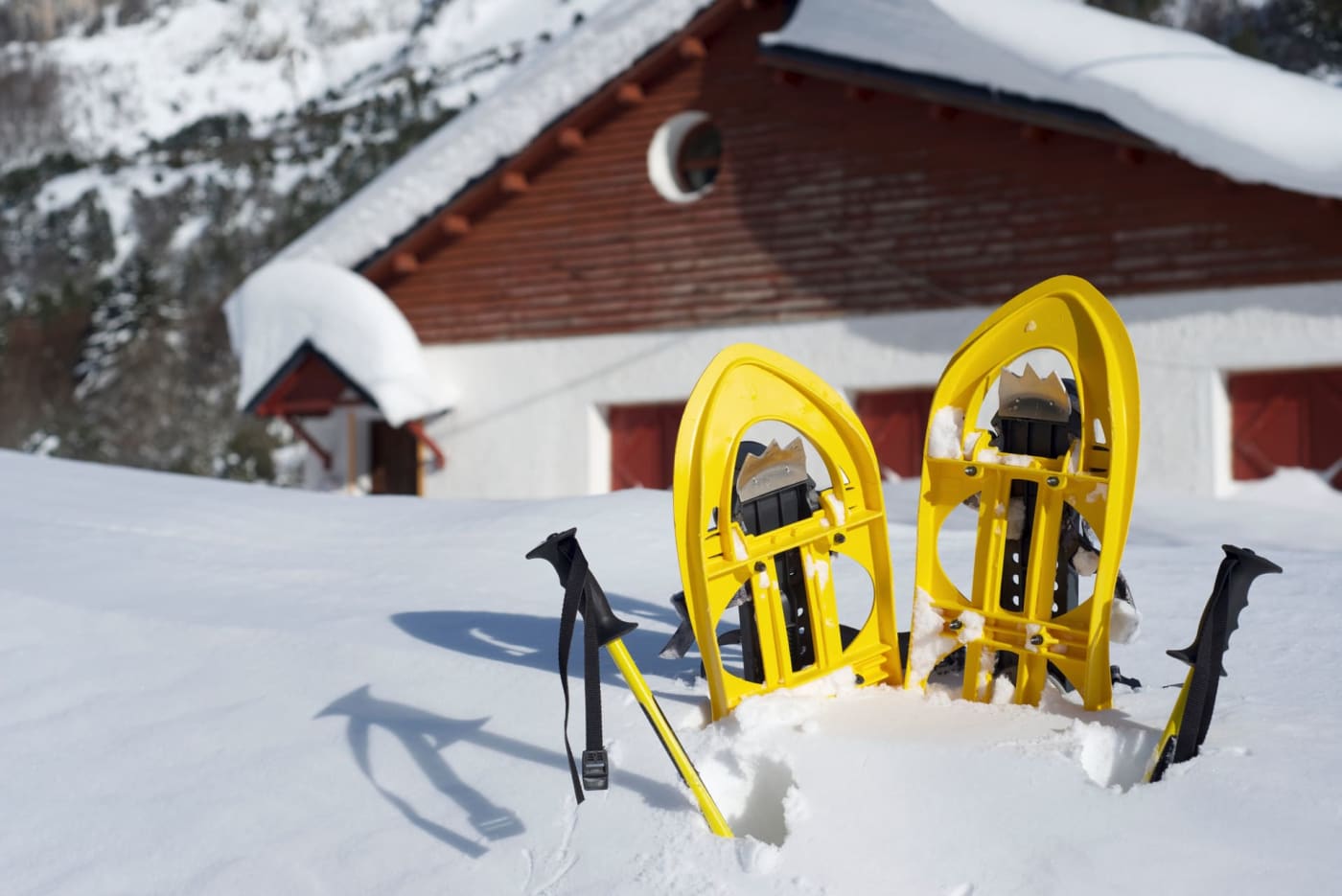 Vacances hiver raquettes : raquettes et bâtons plantés dans la neige devant auberge