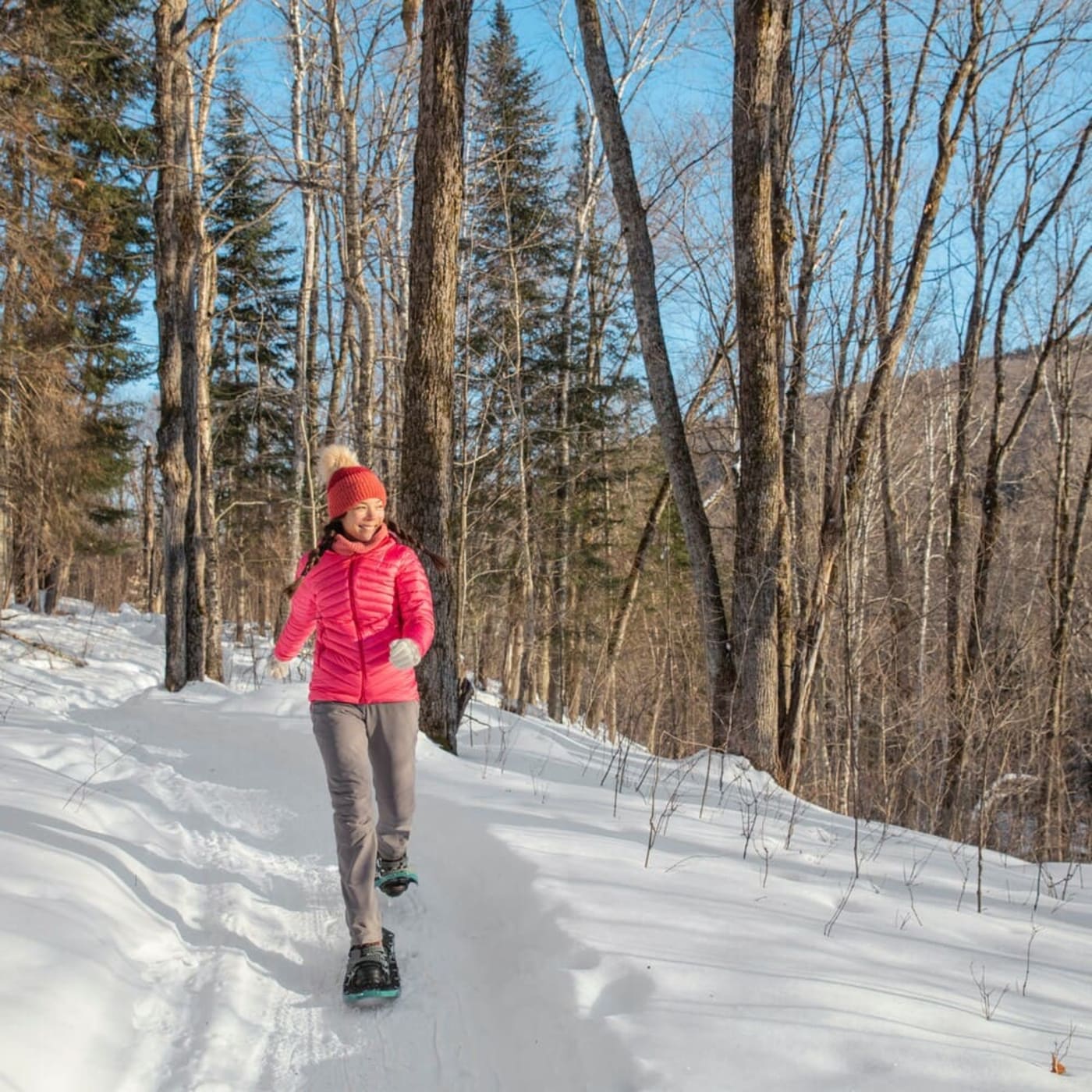 Randonnée raquettes en forêt : une femme se baladant en raquettes dans un bois