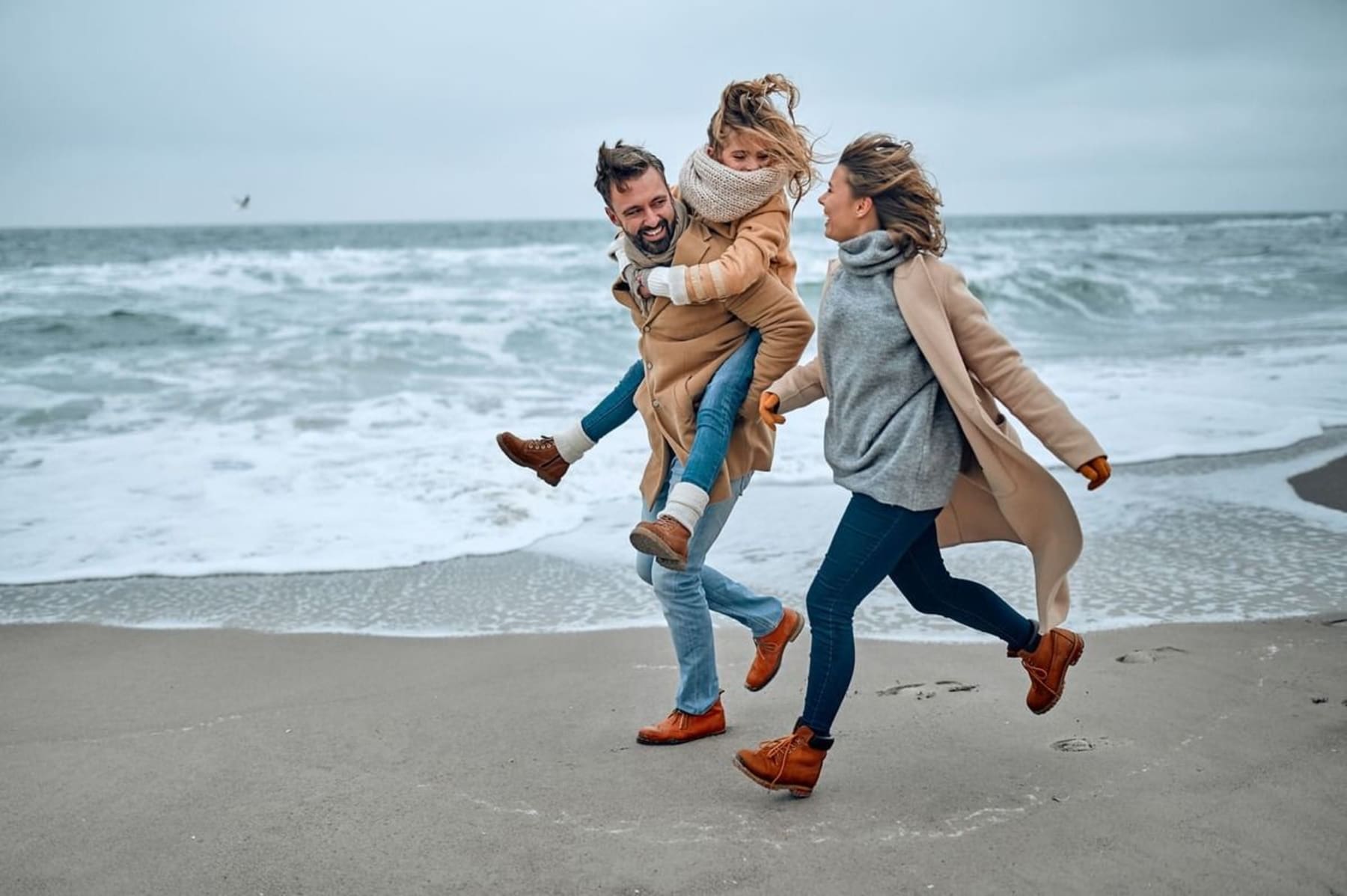 Une famille fait une balade au bord de la plage en hiver