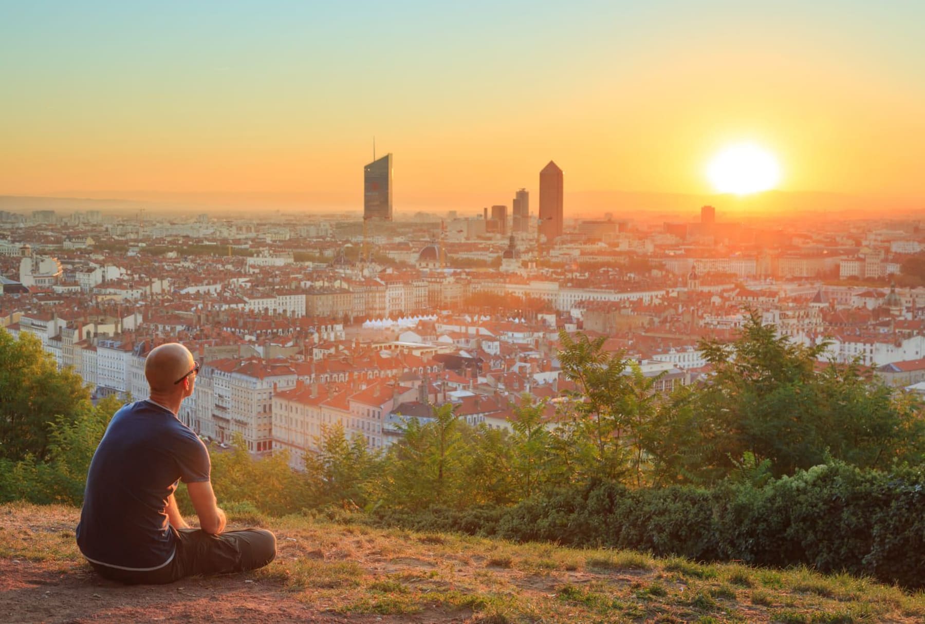 Un randonneur regarde la ville de Lyon depuis la colline de Fourvière pendant le lever de soleil