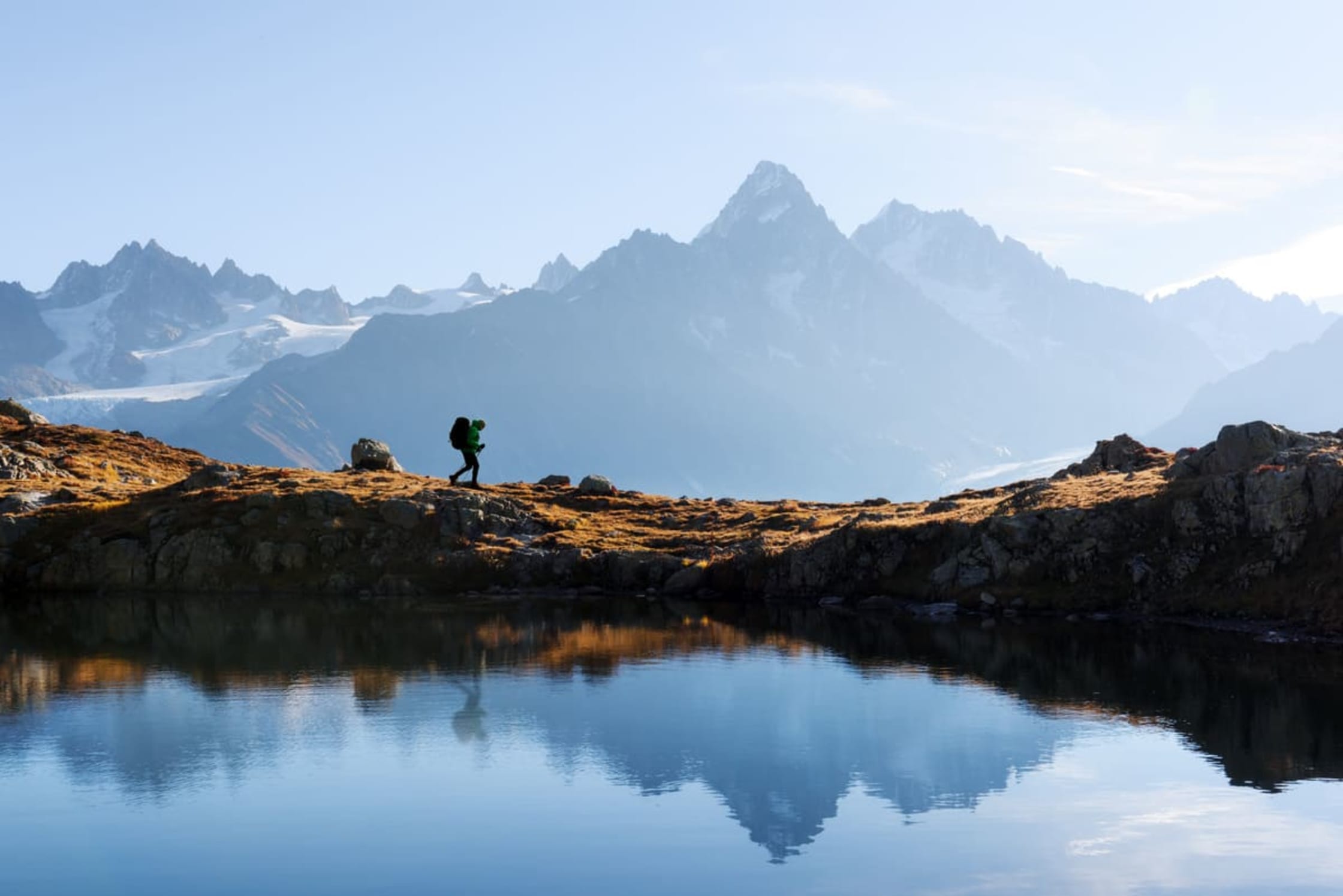 Lacs de Haute-Savoie : randonneur au lac Blanc, vers Chamonix, face aux sommets du Mont-Blanc et reflets dans le lac