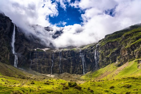 Randonnée et balade à Toulouse : cirque avec herbe verte et cascade tombant des montagnes