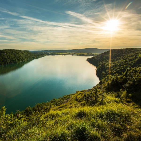 Randonnée lac de Chalain : étendue d'eau turquoise entourée de verdure, soleil brillant