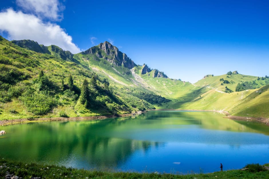 Randonnée lac de Lessy : grande étendue d'eau lisse au pied des montagnes verdoyantes