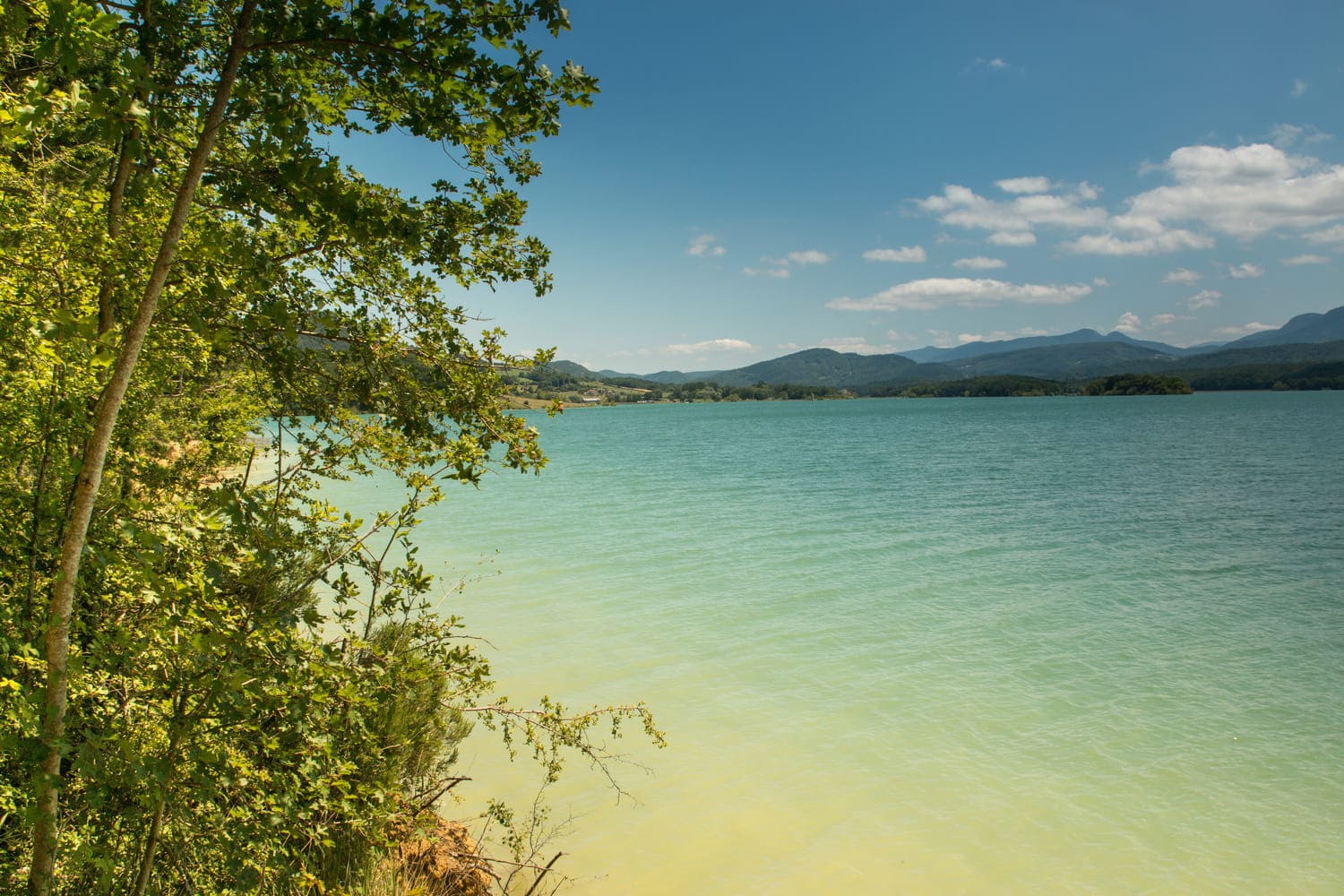 Randonnée lac de Montbel : eau azur, végétation et montagnes au loin