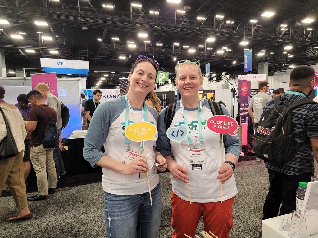 Two women holding signs at React Miami