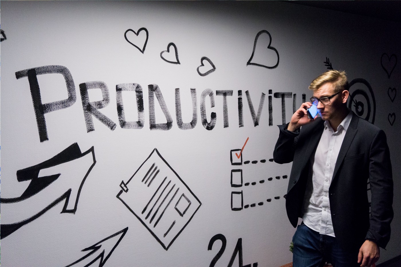 Man on cellphone walking by Productivity board