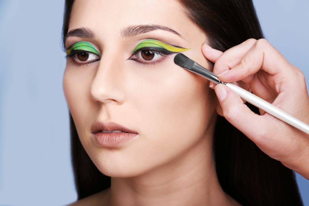 Estilos de maquiagem: imagem mostra mulher sendo maquiada com sombra colorida.
