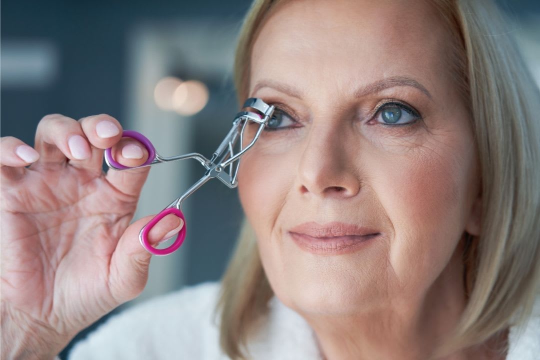 Estilos de maquiagem: imagem mostra mulher sênior se arrumando, utilizando curvex no olho.