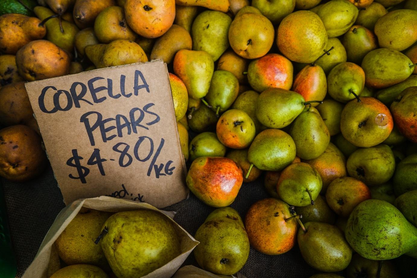 View from above of a display full of pears. A cardboard sign shows the price for a kilo of pears. Once set, fixed prices remain constant over a certain period of time. Read more about fixed price vs. dynamic price in this article!