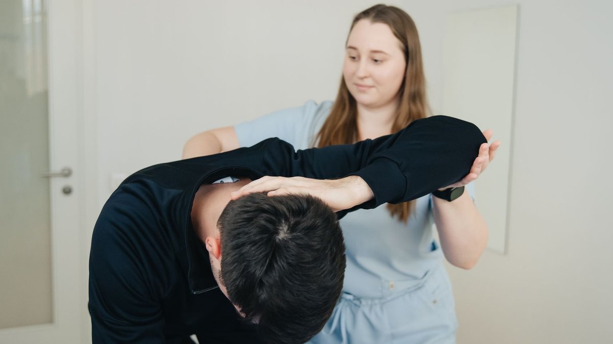 A physiotherapist aids a patient in a stretching exercise for rehabilitation.