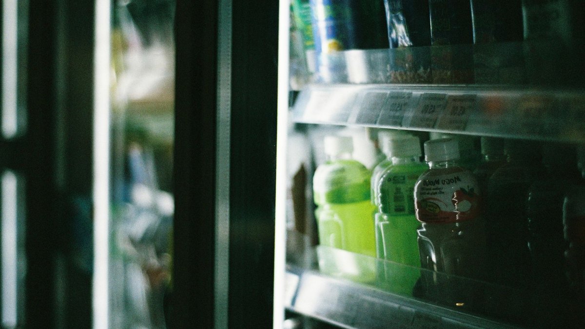 Close-up view of assorted drinks inside a refrigerated store display case.