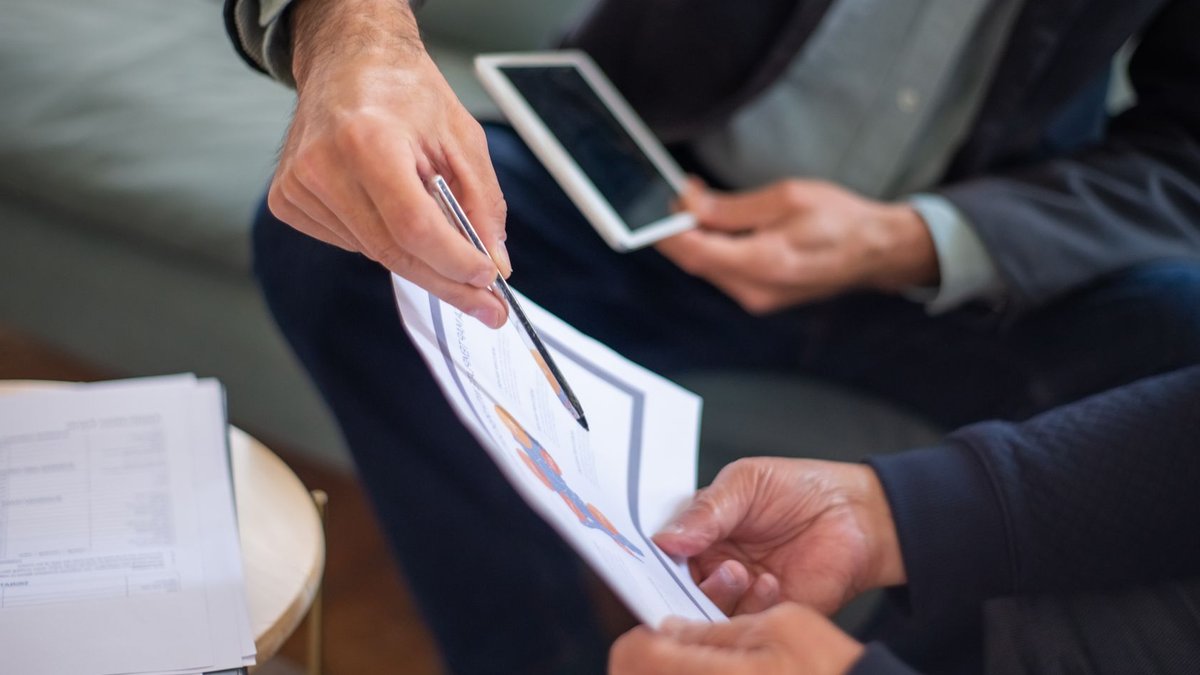 Close-up of two business professionals discussing documents in a meeting.