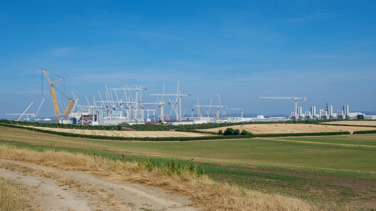 Scenic view of a rural landscape with construction cranes in the background.
