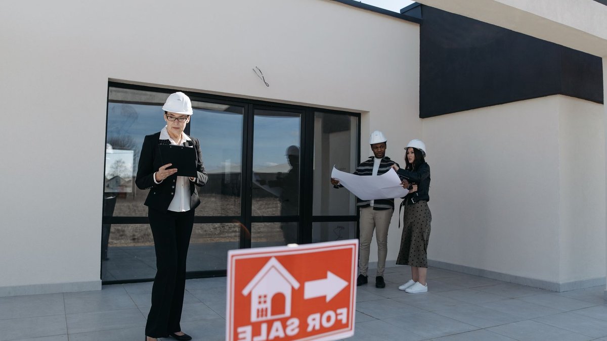 Equity Union Launches Agent Healthcare Program with Trident BPO Real estate agents in hard hats reviewing plans beside a house for sale.