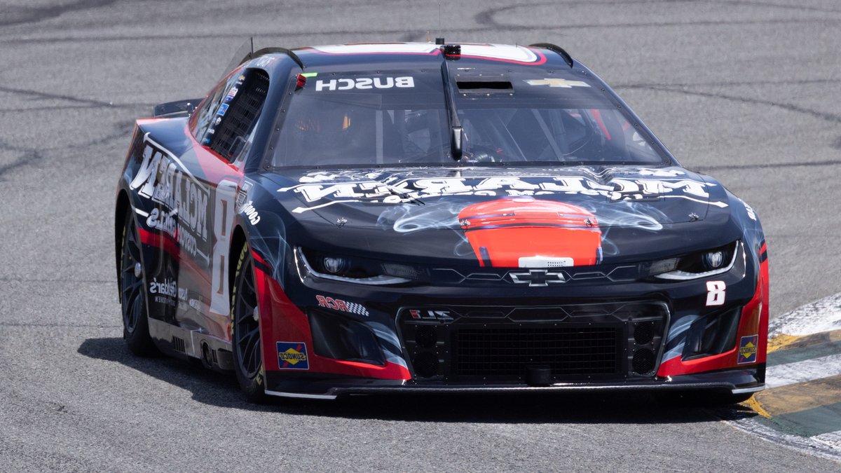 Close-up of a race car speeding on an asphalt track during a daytime race.