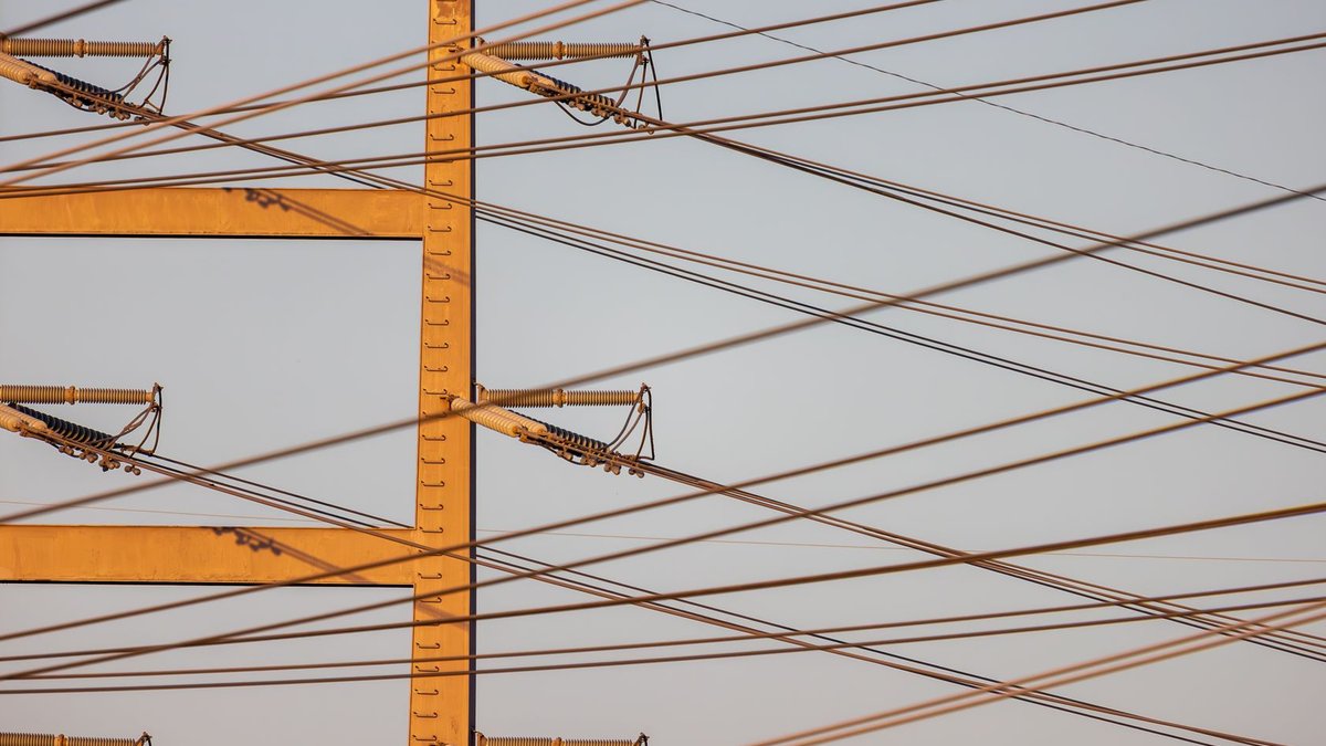 High voltage power lines with sunset sky background, illustrating energy distribution.
