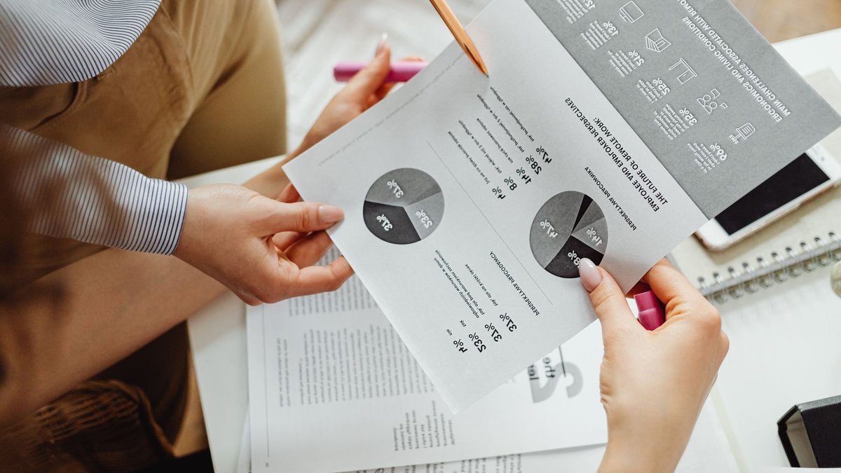 AI Investments Fail to Deliver Promised Productivity Gains Two people reviewing financial reports and graphs at a desk for analysis and decision-making.