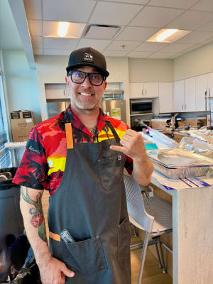 Chef Justin delivering Hawaiian BBQ dishes from the catering menu, dressed in formal attire for the event