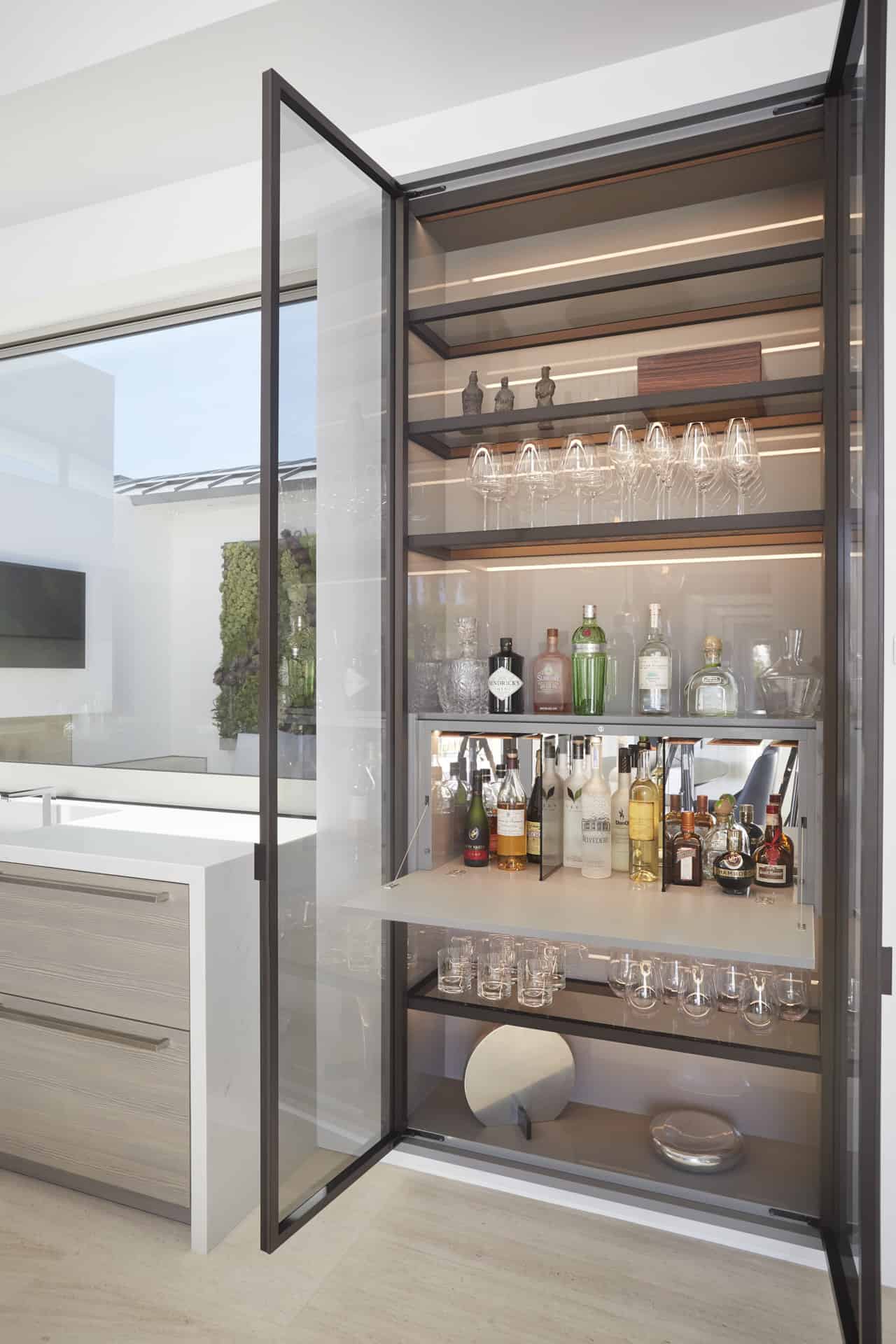 Floating glass-front bar cabinet is convenient as a pass-thru window to the courtyard