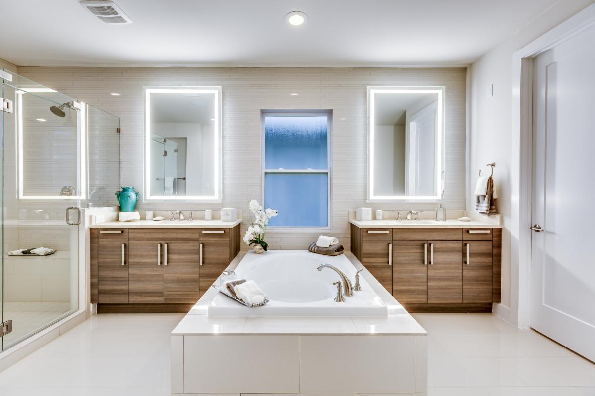 eggersmann-designed luxury bath featuring a garden bath tub in between twin vanities in a wood veneer finish in a home in royal oaks courtyard villas in houston