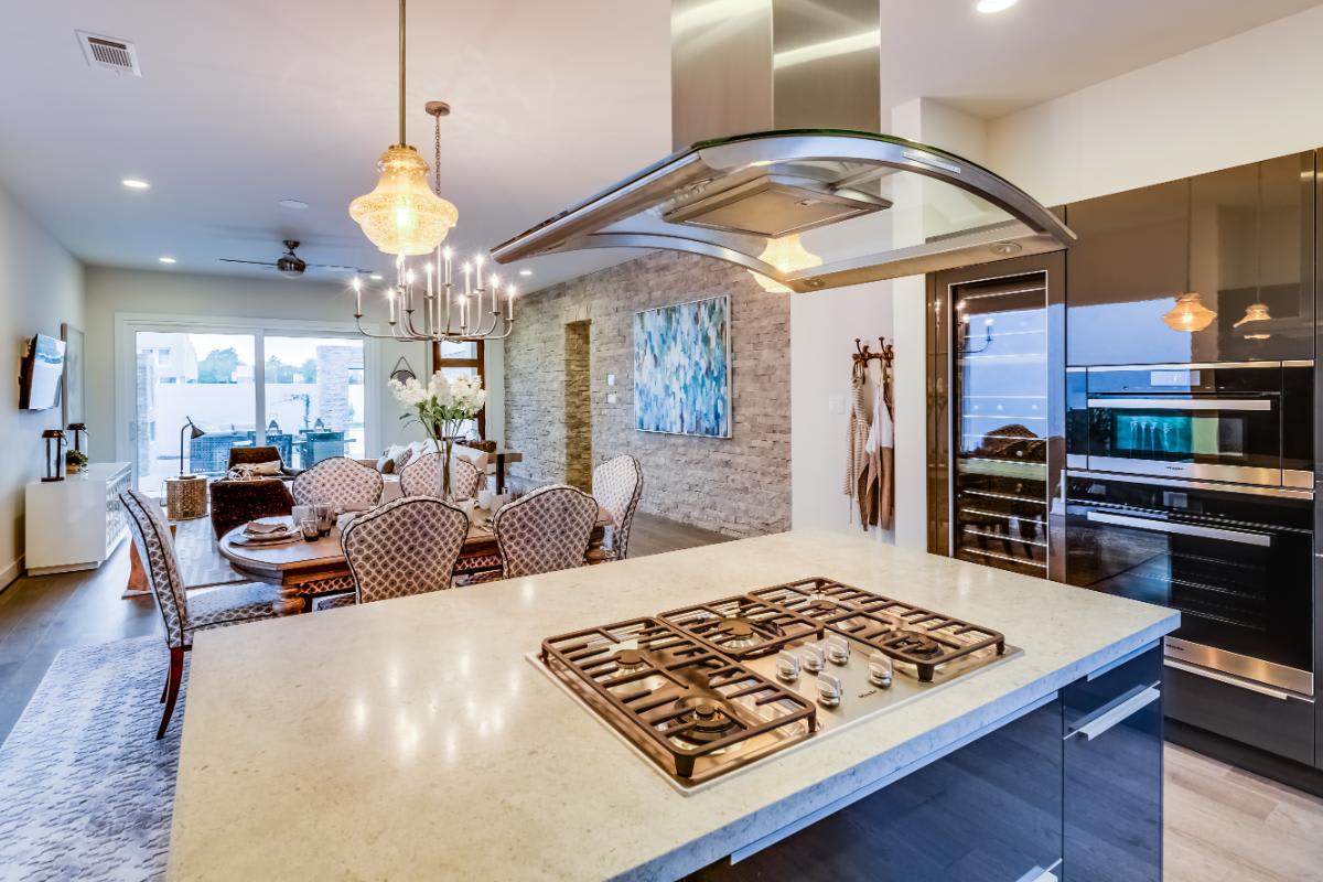 kitchen island wit gas cooktop and glass hood with an appliance wall with wine fridge, microwave, and oven in a garden townhome in royal oaks courtyard villas in houston