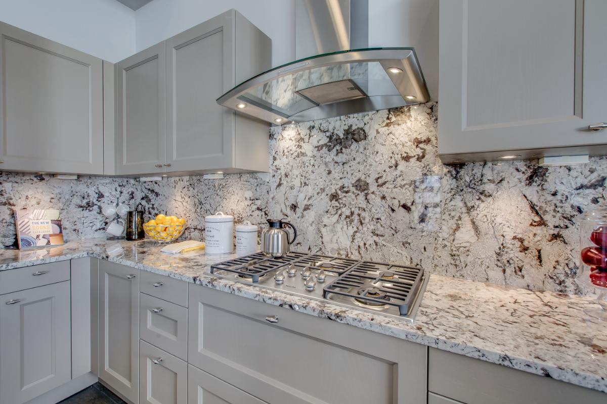 eggersmann-designed kitchen with gas cooktop and glass hood and light taupe decor laminate cabinetry in a residence of royal oaks courtyard villas in houston