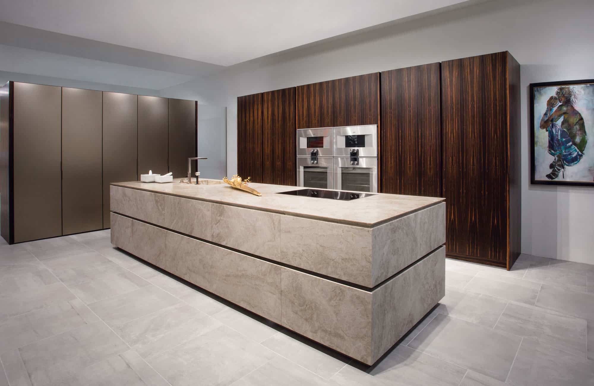 stone kitchen island in taj mahal quartzite with tall cabinets in torino aluminum broze decor melamine finish and appliance wall cabinetry in book-matched noble macassar ebony wood veneer