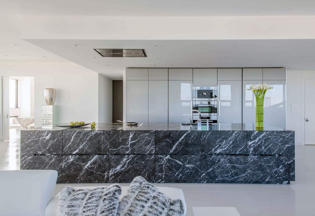 oversized stone island in griogio carnico leaterh limestone with high gloss grey wall cabinets