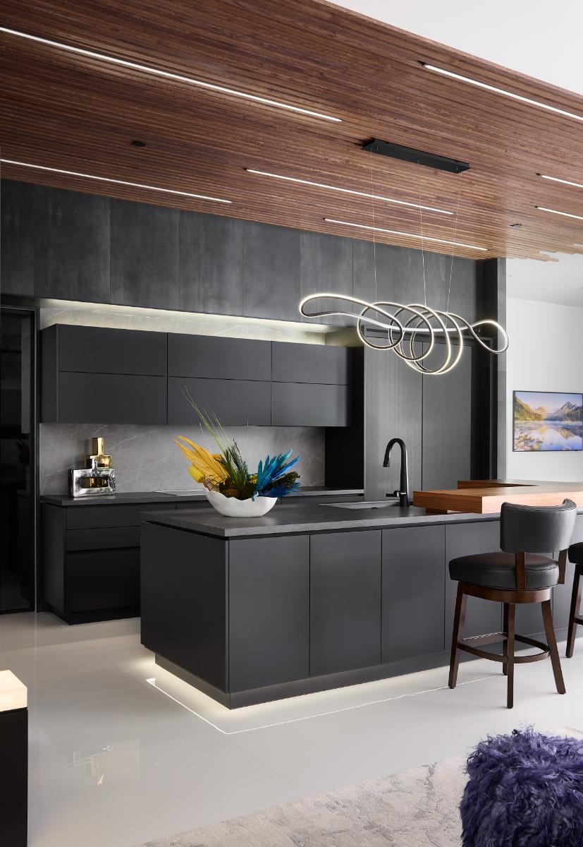 vertically oriented image of a kitchen island and wall cabinetry with work's turnstile pantry closed in a show kitchen of a new construction home in westlake tx