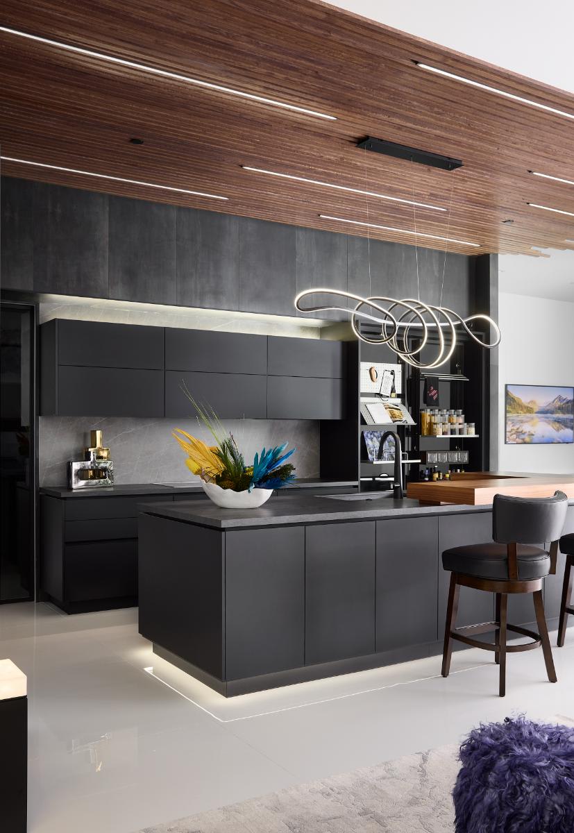 vertically oriented image of a kitchen island and wall cabinetry with work's turnstile pantry open in a show kitchen of a new construction home in westlake tx